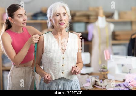 Erwachsene Näherin nimmt Körpermaße von älteren Frauen Stockfoto