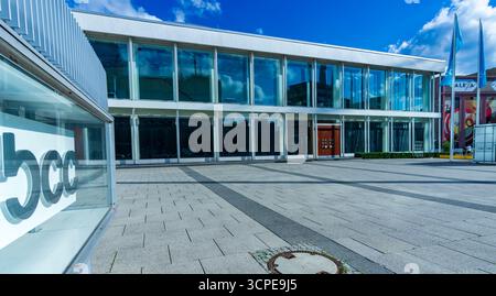 Weitwinkelblick auf die moderne Glasfassade des bcc Berliner Congress Center am Alexanderplatz unter klarem Sommerhimmel. Stockfoto