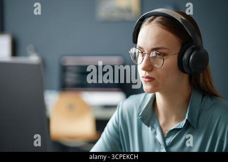 Porträt einer jungen erwachsenen Frau mit Kopfhörerkonzentrat Stockfoto