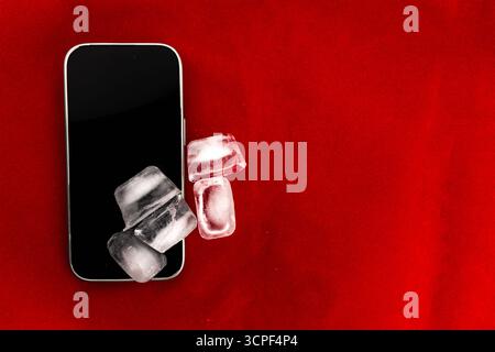 Das Konzept der Überhitzung und Brandgefahr. Kühlung des neuesten Smartphones mit Eiswürfeln. Zu hohe Betriebstemperatur des Prozessors beschädigt das iPhone Stockfoto