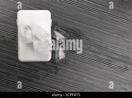 Das Konzept der Überhitzung und Brandgefahr. Kühlung des neuesten Smartphones mit Eiswürfeln. Zu hohe Betriebstemperatur des Prozessors beschädigt das iPhone Stockfoto