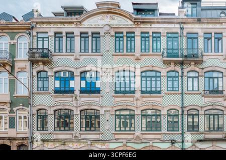 Breite Fassade des Porto-Gebäudes mit grün-weiß karierten Azulejo-Tiling, verzierten Steindetails und grünen Fensterrahmen. Historische Innenstadt Stockfoto