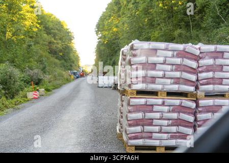 Stapelpaletten mit Baustoffen säumen eine Schotterstraße im Wald, Baustelle Hermann Hessebahn, Calw, Deutschland Stockfoto