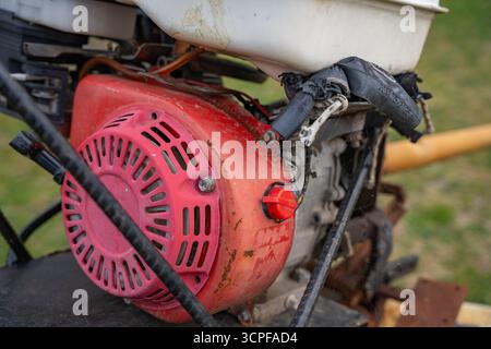 Alter verschmutzter, rostiger Generatormotor mit Kühlerlüfter und mechanischen Teilen. Verwitterte und veraltete Industriemaschinen. Anzeichen von Verschleiß und Korrosion Stockfoto