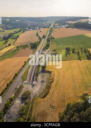 Felder und Gleise, parallel zu einer Straße, umgeben von Bäumen, mit Blick auf ein entferntes Dorf, Bau der Hermann-Hessen-Bahn, Calw Stockfoto