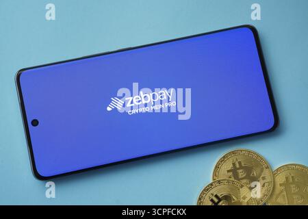 Dhaka, Bangladesch, 03. September 2025: Zebpay-Logo auf dem Smartphone-Bildschirm neben Bitcoin-Coin und QR-Code auf blauem Hintergrund Stockfoto