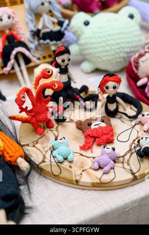 Ein Set gehäkelter Amigurumi-Spielzeuge in Form von fiktiven Figuren. Eine Sammlung gestrickter Spielzeuge auf einem Holzständer. Handgefertigte Miniaturfiguren: A Stockfoto