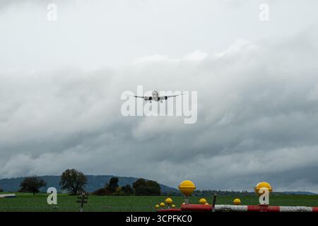 Kommerzielles Passagierflugzeug, das zur Landung absteigt, Vorderansicht. Bewölkter Herbsttag, Nahaufnahme, Teleaufnahme, ebenerdig, Blick nach oben Stockfoto