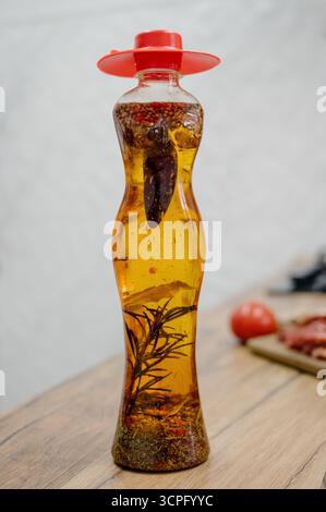 Hausgemachtes ätherisches Öl mit Gewürzen und Rosmarin in einer klaren Flasche. Nahaufnahme einer Flasche ätherischen Öls gefüllt mit Rosmarin und Pfeffer Stockfoto