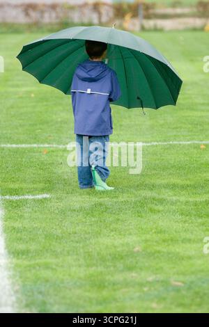 Junge, der mit einem Regenschirm auf dem Fußballfeld spielt, Maine. Stockfoto