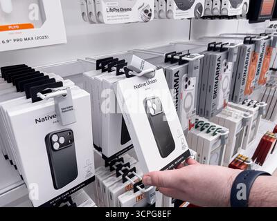 Poznan, Polen – 20. September 2025: Die Verpackung der iPhone 17 Pro Native Union Handyhülle wird von einem Kunden gehalten, der Zubehör in einem geschäftigen Verkaufsregal durchsucht Stockfoto
