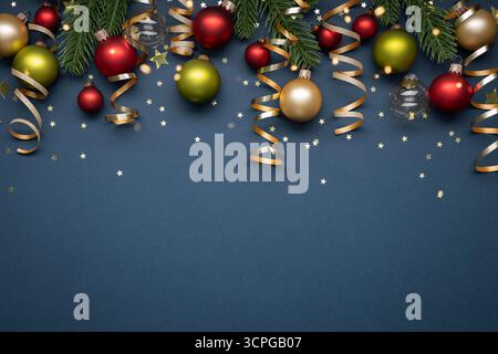 Weihnachtskugeln, Tannenbrunches und goldene Dekorationen auf dunkelblauem Hintergrund. Grußkarte zu Weihnachten und Neujahr Stockfoto