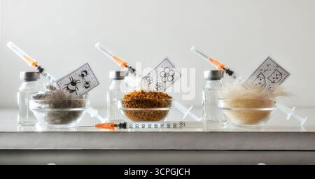 Hintergrund mit verschiedenen Allergenen wie Milben, Pollen und Tierhaaren auf einem weißen Tisch mit mehreren Dosen Impfstoff in Durchstechflaschen und einer Spritze. Vorne Stockfoto