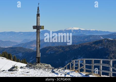 Gipfelkreuz in einem Skigebiet in österreich mit atemberaubendem Fernblick auf verschneite Bergketten. Blauer Himmel mit Kopierraum. Stockfoto