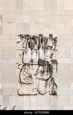 Wandschnitzerei an der Außenseite, die historische Figuren zeigt, die in einer antiken Umgebung an verschiedenen Aktivitäten beteiligt waren Stockfoto