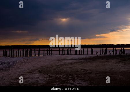 Eine atemberaubende und dramatische Weitwinkellandschaft einer Salzmündung (wie Kuyalnik Mündung) bei Sonnenuntergang. Der Himmel ist voller dunkler, schwerer Wolken, aber ein bri Stockfoto
