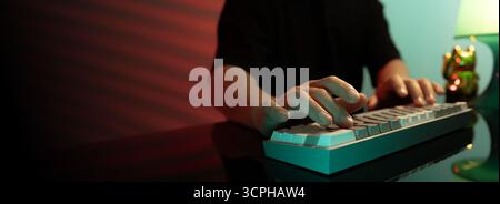 Filmisches rot-grünes Foto einer Person, die in gemütlicher Atmosphäre an einer Tastatur arbeitet. Konzept für Fernarbeit, Freiberufung und modernen digitalen Lebensstil Stockfoto