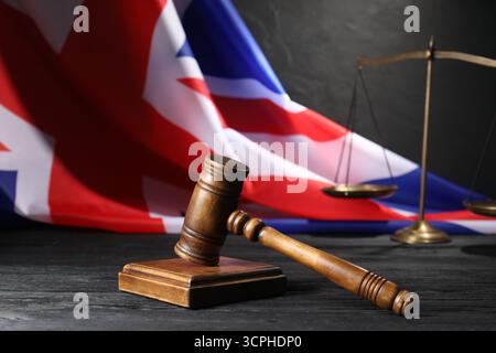 Richterlicher Hammer, Flagge von Großbritannien und Waage auf schwarzem Holztisch, Nahaufnahme Stockfoto