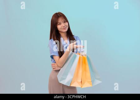 Glückliche junge Frau mit bunten Einkaufstaschen, die Shopping, Stil und positive Stimmung demonstrieren Stockfoto