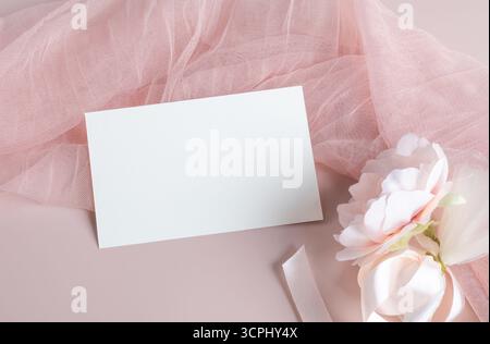 Weiße leere Kartenmockup-Vorlage auf hellem pastellrosa Stoff auf rosa Hintergrund, Designelement für Hochzeits-rsvp, Dankeskarte, Gruß oder Einladung Stockfoto