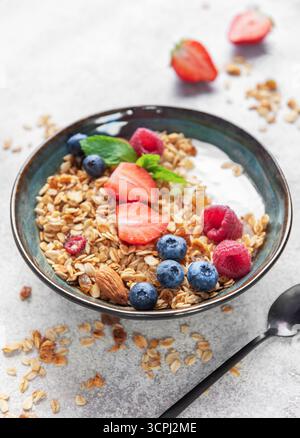 Müslischale gefüllt mit Joghurt, frischen Beeren, Mandeln und Pfefferminze für ein gesundes Frühstück Stockfoto