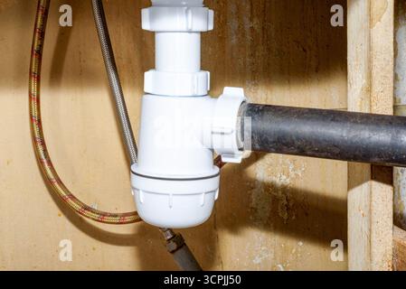 Eine neue Sanitärfalle unter dem Spülbecken und alte Abflussrohre. Haushaltsalltag. Stockfoto