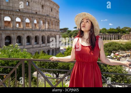 Ein Mädchen mit Hut besucht Rom, Italien. Ein Panoramablick auf das Kolosseum befindet sich im Hintergrund. Stockfoto