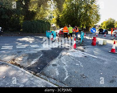 Manchester, Vereinigtes Königreich – 23. September 2025: Bauarbeiter in Warnwesten führen an einer blockierten Kreuzung in Manchester Straßenreparaturen durch. Stockfoto
