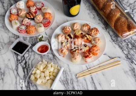 Genießen Sie köstliches Sushi und eine Auswahl an Snacks, die kunstvoll auf einem Marmortisch präsentiert werden Stockfoto
