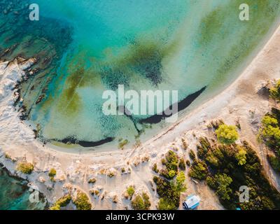 Panoramablick auf den Karidi Beach in Sithonia, Griechenland, mit markanten türkisfarbenen Wasserstrukturen und sandiger Küste. Morgenlicht Stockfoto