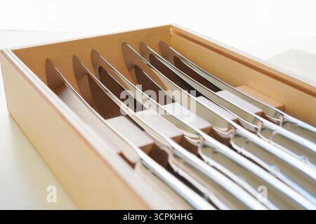 Nahaufnahme von Steakmessern in einer Holzkiste auf weißem Hintergrund Stockfoto