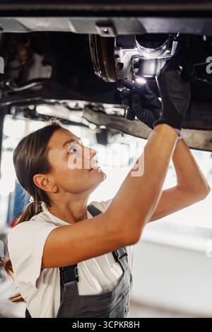 Ein hochqualifizierter Mechaniker, der an einem Fahrzeug zur Wartung arbeitet Stockfoto