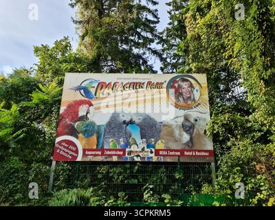 Bochum, Deutschland - 25. September 2025: Papageien Park Bochum Werbetafeln, die verschiedene Papageienarten im grünen Laub bewerben Stockfoto
