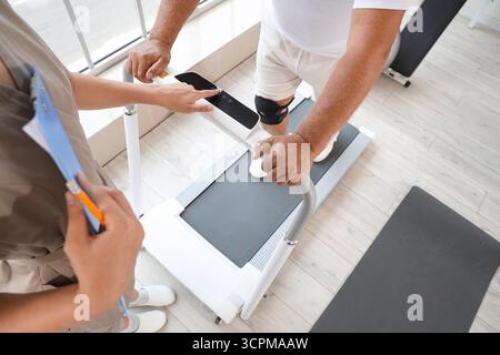 Seniorenausbildung mit Therapeutin auf Laufband im Rehabilitationszentrum, Draufsicht Stockfoto