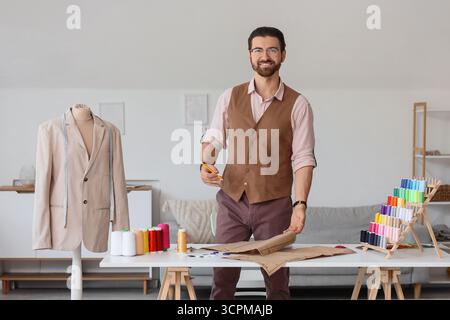 Männlicher Schneider, der mit Muster am Tisch im Atelier arbeitet Stockfoto