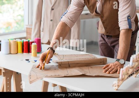 Männlicher Schneider, der mit Muster am Tisch im Atelier arbeitet Stockfoto