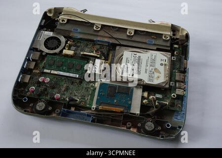 Abriss eines alten Notebook-Laptops auf weißem Hintergrund. Laptop-Komponenten wie Festplatte, Speicher, RAM, Chipsatz, Akku, Mainboard und andere. Stockfoto
