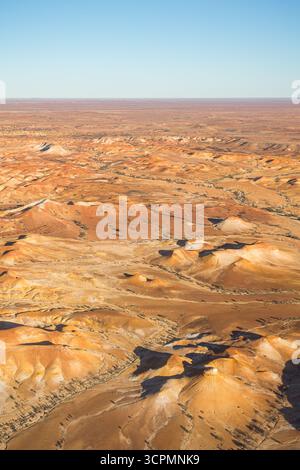 Aus der Vogelperspektive der Painted Desert in Australien zeigt eine riesige Weite erodierter Hügel in satten Rot-, Orange- und Brauntönen. Stockfoto