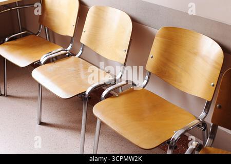Holzstühle im Warteraum der Klinik. Krankenhaus-Gesundheitswesen-Innenraum mit leeren Sitzen. Ort für Patienten vor Arzttermin. Stockfoto