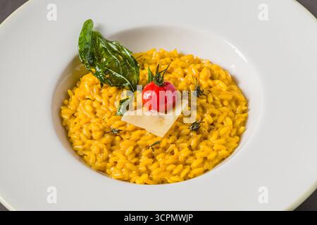 Stachelpilz-Risotto auf einem weißen Porzellanteller auf einem Steintisch Stockfoto