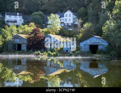 Nebelige Morgenspiegelung von Bootshäusern und Hütten am Lake Windermere, Lake District, Cumbria, England Stockfoto