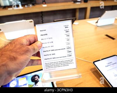 Paris, Frankreich - 19. September 2025: Nahaufnahme einer Hand mit transparentem Display mit iPad-Modellen und Preisen in einem Apple Store, einschließlich iPad Mini, Air und Pro Optionen. Stockfoto
