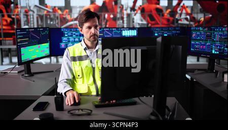 Leitender Produktionsingenieur überwacht das SCADA-System auf Desktop-PCs für Kraftfahrzeugwerke. Stockfoto