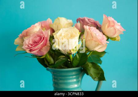 Strauß aus rosa und weißen Rosen in einer blauen Vase auf hellem Hintergrund Stockfoto