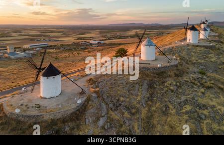 Luftaufnahme der historischen Windmühlen von Consuegra bei Sonnenaufgang, Castilla-La Mancha, Spanien. Alte historische Windmühlen mit Don Quijote Charakter auf den Hügeln Stockfoto