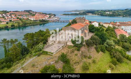 Aus der Vogelperspektive San Vicente de la Barquera, Kantabrien, Nordspanien. Orbit-Drohnenaufnahme der Kirche Santa Maria de los Angeles in San Vicente Stockfoto