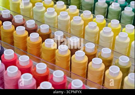 Viele Garnspulen in verschiedenen Farben, Nahaufnahme, abstrakter Textilindustrie Hintergrund Stockfoto