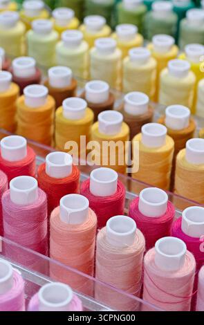 Viele Garnspulen in verschiedenen Farben, Nahaufnahme, abstrakter Textilindustrie Hintergrund Stockfoto