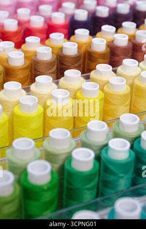 Viele Garnspulen in verschiedenen Farben, Nahaufnahme, abstrakter Textilindustrie Hintergrund Stockfoto