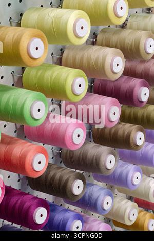 Viele Garnspulen in verschiedenen Farben, Nahaufnahme, abstrakter Textilindustrie Hintergrund Stockfoto